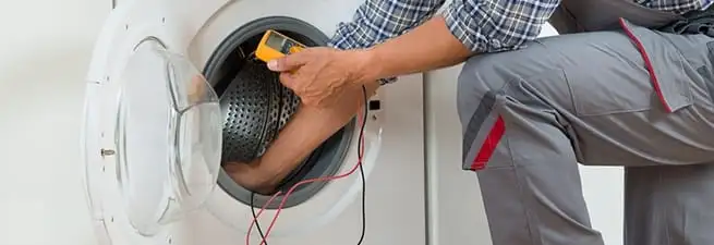 Dryer repair technician inspecting and repairing a clothes dryer in Lakewood, CO