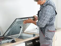 Appliance repair technician installing a built-in cooktop in Lakewood, CO