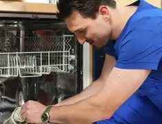 Dishwasher repair technician inspecting and servicing an open dishwasher in Lakewood, CO