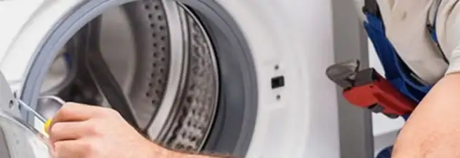 Appliance technician repairing a clothes dryer drum and internal parts in Lakewood, CO