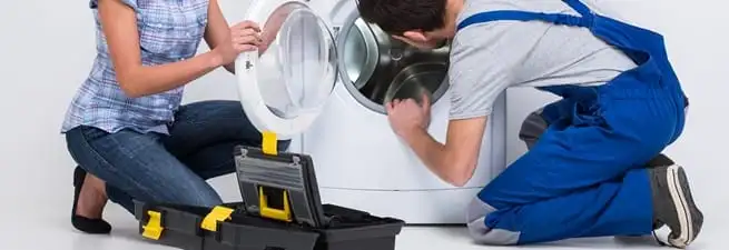Washer repair technician inspecting a front-load washing machine with tools in Lakewood, CO