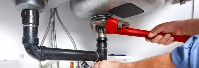 Garbage disposal repair technician tightening the sink drain and disposal connection in Lakewood, CO