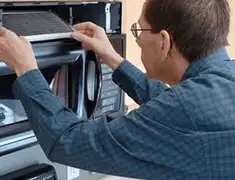 Appliance repair technician replacing a microwave vent filter in Lakewood, CO