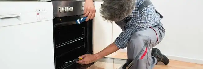Oven repair technician inspecting and servicing an electric oven in Lakewood, CO