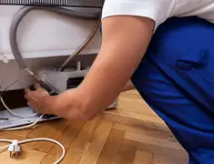 Appliance repair technician fixing refrigerator water line and connections in Lakewood, CO