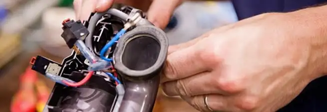 Vacuum repair technician reconnecting wiring and components in Lakewood, CO