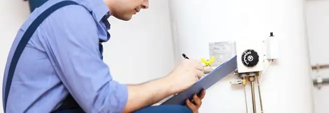 Water heater repair technician inspecting the unit and recording service notes in Lakewood, CO